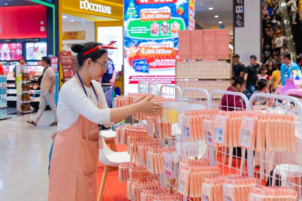 A woman in an apron standing in front of a display of small items